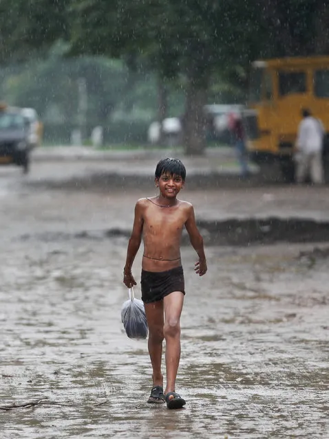 An Indian boy walks during sudden downpour in New Delhi, India, Friday, July 10, 2015. India's monsoon season, which runs from June to September, bring rains that are vital to agriculture. (Photo by Altaf Qadri/AP Photo)
