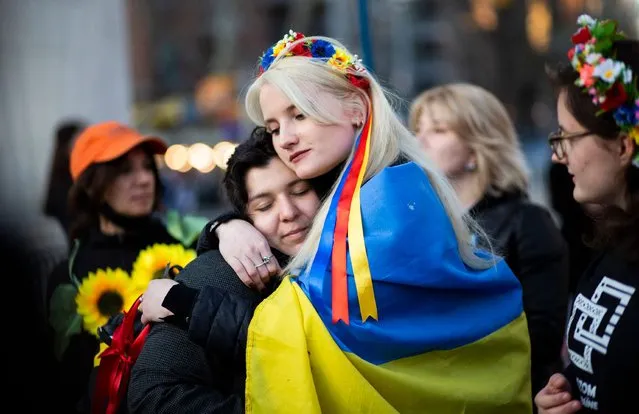 Women, wrapped in a Ukrainian flag, embrace during a flash mob protesting sexual abuse by Russian soldiers in Ukraine, at Washington Square Park in New York, April 8, 2022.  (Photo by Kena Betancur/AFP Photo)