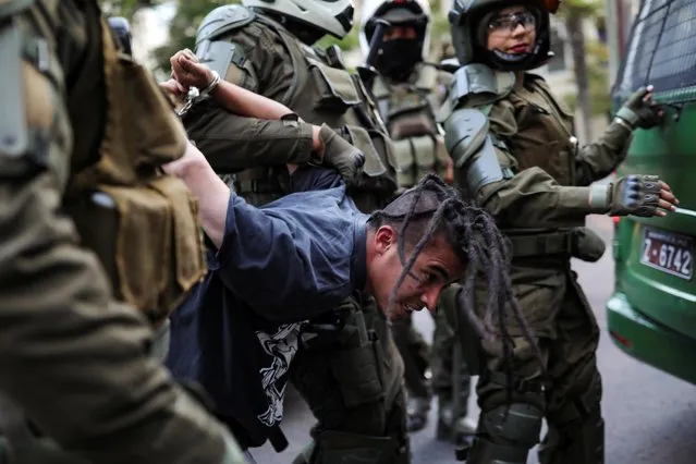 Riot policemen detain a demonstrator during a protest against Chile's government, at Providencia, a wealthy neighbourhood, in Santiago, Chile on December 3, 2019. (Photo by Pablo Sanhueza/Reuters)