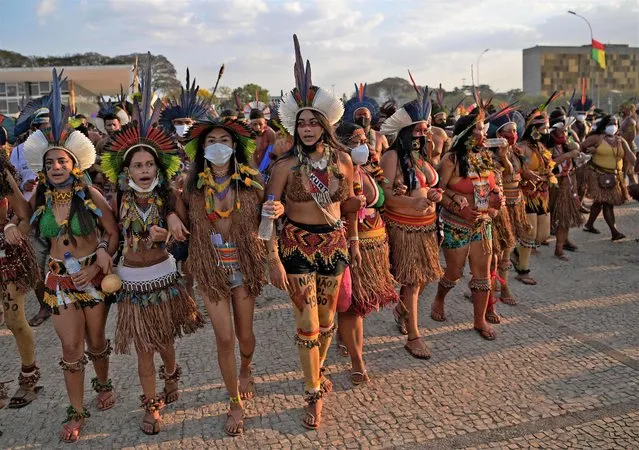 Indigenous women protest outside the Supreme Court in Brasilia on August 26, 2021. Thousands of indigenous protesters gathered in the Brazilian capital bearing bows and arrows and traditional headdresses as the Supreme Court prepared to take up a case that could eliminate reservations on their ancestral lands. (Photo by Carl de Souza/AFP Photo)