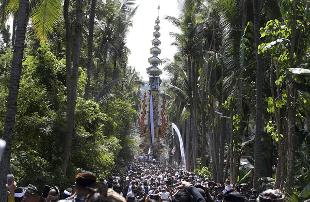 Men carry the cremation tower containing the remains of 220 people during traditional mass cremation called “'ngaben'” on Wednesday, August 14, 2024, in Manggis, Bali, Indonesia. (Photo by Firdia Lisnawati/AP Photo)