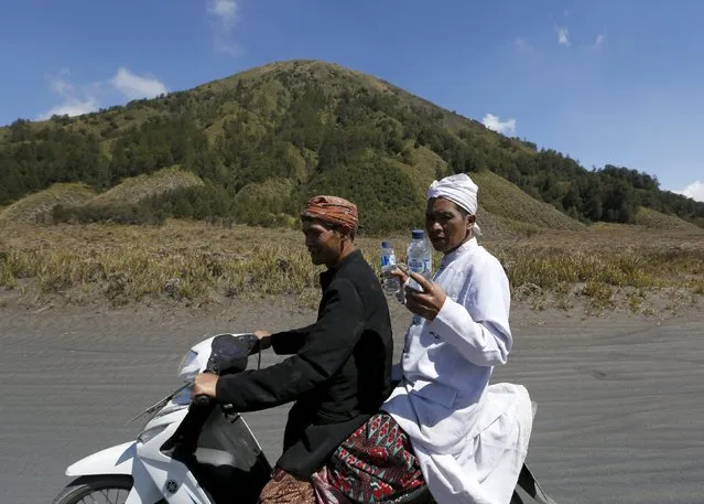 Hindu villagers ride a motorcycle as they carry bottles of holy water they collected for prayers ahead of the annual Kasada festival at Mount Bromo in Indonesia's East Java province, July 30, 2015. (Photo by Reuters/Beawiharta)