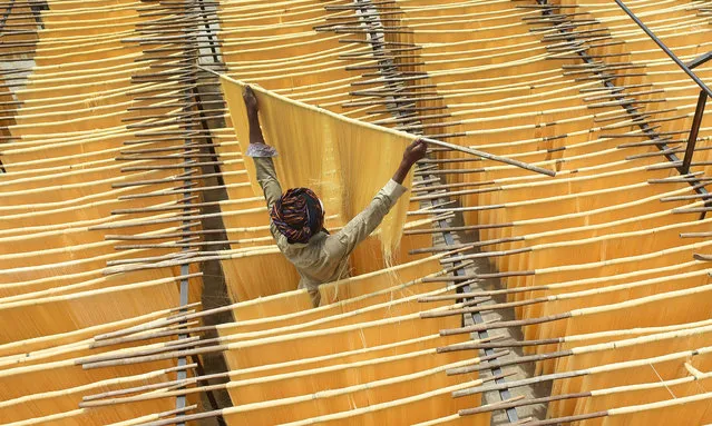 A Pakistani man dries Seviiyan (thin vermicelli), which is used for the preparation of “sheerkhurma”, a traditional sweet dish prepared by the Muslim community during the holy month of Ramadan, at a factory in Lahore on June 8, 2017. (Photo by Arif Ali/AFP Photo)