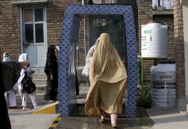 In this Monday, September 14, 2020 file photo, students walk through a disinfectant tunnel as they arrive to Benazir Bhutto Women University for an examination ahead the university reopening in Peshawar, Pakistan. As coronavirus vaccines trickle into some of the poorest countries in Asia, Africa and the Middle East, data suggest some women are consistently missing out, in another illustration of how the doses are being unevenly distributed around the world. (Photo by Muhammad Sajjad/AP Photo)