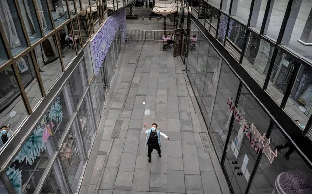 A worker plays badminton with a colleague next to closed shops in the nearly empty shopping area of the usually bustling Taikoo Li mall after many retail stores were closed to help prevent the spread of COVID-19 on May 10, 2022 in Beijing, China. China is trying to contain a spike in coronavirus cases in the capital Beijing after hundreds of people tested positive for the virus in recent weeks, causing local authorities to initiate mass testing in most districts, close schools and stores, ban gatherings and inside dining in all restaurants, and to lockdown some neighbourhoods in an effort to maintain the country's zero COVID strategy.(Photo by Kevin Frayer/Getty Images)