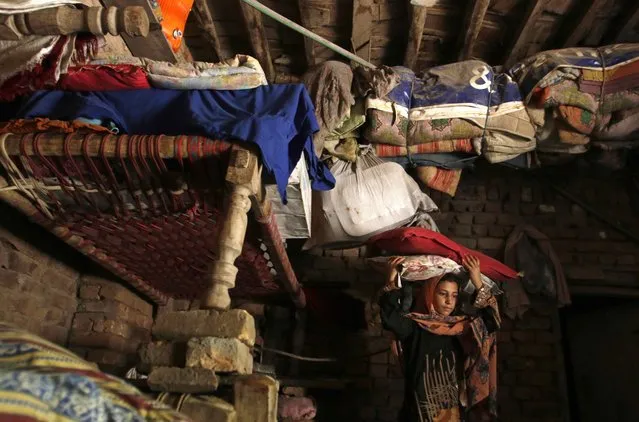 A girl moves bedding to top bunks at her home after heavy rainfall caused flooding in Peshawar, Pakistan, July 27, 2015. (Photo by Khuram Parvez/Reuters)