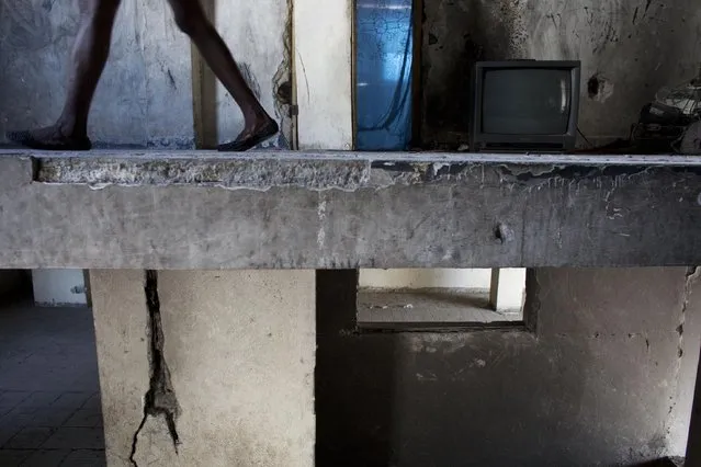 In this June 29, 2015 photo, Zarmor Sendi walks along the stairwell of the abandoned, earthquake damaged government building where she's living in Port-au-Prince, Haiti. Sendi, 28, lost her home in the quake and was later evicted from a camp set up for those displaced by the quake. (Photo by Rebecca Blackwell/AP Photo)
