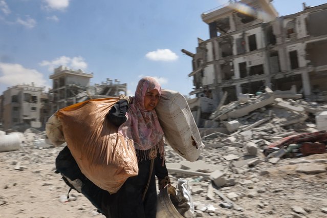 A Palestinian woman who retuned briefly to eastern Deir al-Balah in the central Gaza Strip to check on her home, carries away some items that she was able to salvage amid the rubble, after Israeli troops pulled out from some blocks in the area on August 29, 2024, amid the ongoing conflict between Israel and the Hamas militant group. (Photo by Eyad Baba/AFP Photo)