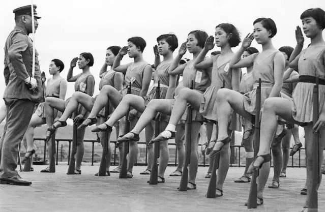 Japanese chorus girls appear to be drilling in military tactics atop their theater building as they perform salutes, June 30, 1937. The officer is from the Japanese regular army and says the girls display more rhythm in their drills than do the regular troops. (Photo by AP Photo)