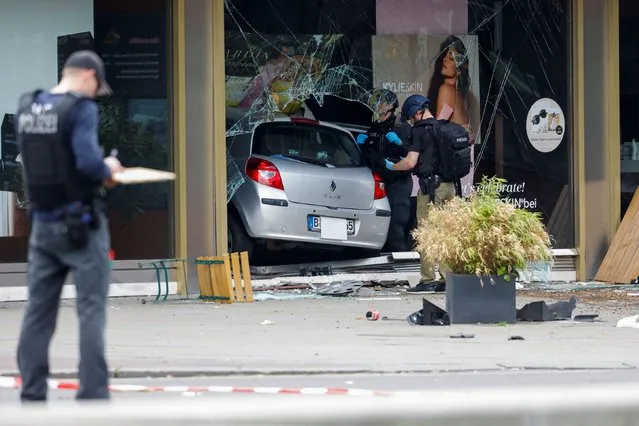 Police officers stand next to a car that crashed into a group of people and ended up in a storefront near Breitscheidplatz in Berlin, Germany, June 8, 2022. (Photo by Michele Tantussi/Reuters)