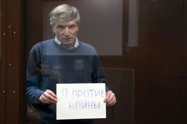 Alexei Gorinov holds a sign “I am against the war” standing in a cage during hearing in the courtroom in Moscow, Russia, Tuesday, June 21, 2022. Moscow's Meshchansky District Court ruled Tuesday that Alexei Gorinov, a member of the municipal council in one of Moscow's districts, should stay in custody pending his trial on charges of discrediting the country's armed forces. (Photo by Alexander Zemlianichenko/AP Photo)