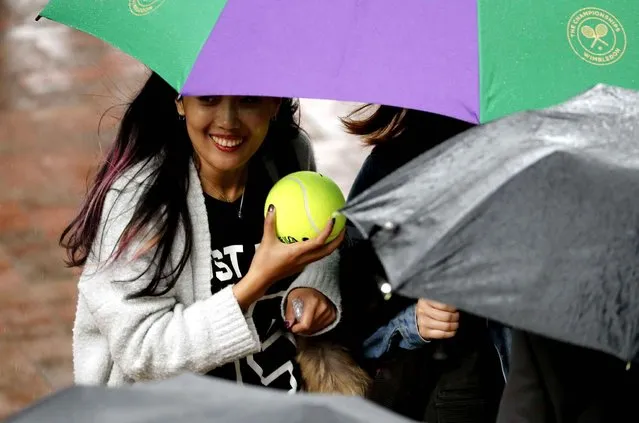 Spectators take shelter under umbrellas as rain delays play during day five of the Wimbledon Tennis Championships in London, Friday, July 1, 2016. (Photo by Ben Curtis/AP Photo)