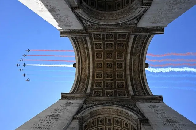 Alphajets from the French Air Force Patrouille de France release trails of red, white and blue smoke, colors of French national flag, over the Arc de Triomphe during a rehearsal, three days ahead of the Bastille Day parade on the Champs-Elysees avenue, on July 11, 2022 in Paris. (Photo by Emmanuel Dunand/AFP Photo)