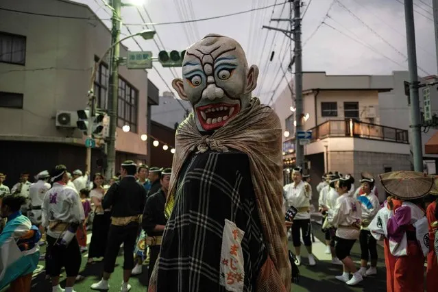 This photo taken on August 16, 2017 shows a dancer disguised as an imaginary monster in Japanese folklore walking on a street at the Ikeda Awa Odori Festival in the city of Miyoshi, about 80 kms west of Tokushima, Tokushima prefecture, on Japan's Shikoku island. Various places in Tokushima prefecture hold the annual Awa Odori festival during “obon”, an annual Buddhist period in August to welcome ancestors' souls which are believed to return to this world and visit their families. (Photo by Yasuyoshi Chiba/AFP Photo)