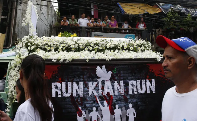 Residents watch the passing funeral precession of slain Kian Loyd delos Santos, a 17-year-old student, Saturday, August 26, 2017, in suburban Caloocan city north of Manila, Philippines. The killing of Kian by police has sparked an outcry against President Rodrigo Duterte's anti-drug crackdown, which has left thousands dead since assuming office in June of last year. (Photo by Bullit Marquez/AP Photo)
