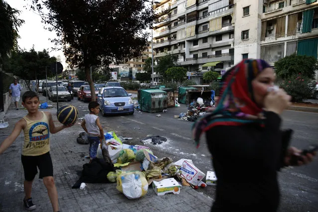 A Lebanese woman covers her nose from the smell as she walks on a street partly covered by piles of garbage in Beirut, Lebanon, Sunday, July 26, 2015. Protesters have closed the highway linking Beirut with southern Lebanon over the country's trash crisis. (Photo by Hassan Ammar/AP Photo)