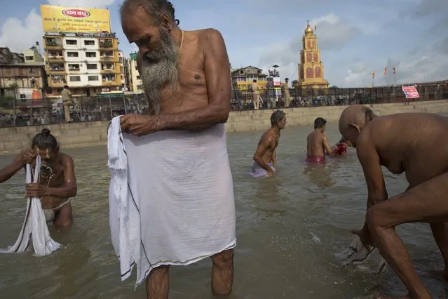 Indian Sadhus, or Hindu holy men bath in the Godavari River during Kumbh Mela, or Pitcher Festival in Nashik, India, Saturday, August 29, 2015. Hindus believe taking a dip in the waters of a holy river during the festival will cleanse them of their sins. (Photo by Tsering Topgyal/AP Photo)