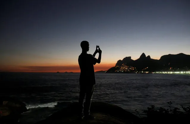 A man takes pictures of sunset on the rocks of Arpoador beach in Rio de Janeiro, Brazil, May 2, 2016. (Photo by Nacho Doce/Reuters)