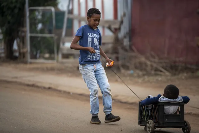 A young boy plays with his brother on the street in Thokoza, east of Johannesburg, South Africa, Friday, April 3, 2020. South Africa went into a nationwide lockdown for 21 days in an effort to control the spread of the coronavirus. (Photo by Themba Hadebe/AP Photo)