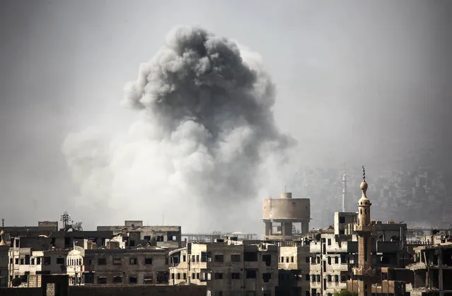 Smoke billows from buildings following a reported air strike on Ain Tarma in the Eastern Ghouta area, a rebel stronghold east of the Syrian capital, on October 2, 2017. (Photo by Amer Almohibany/AFP Photo)