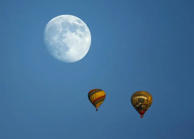 Hot air balloons makes their way past a rising moon as the sun sets near Encinitas, California September 6, 2014. (Photo by Mike Blake/Reuters)