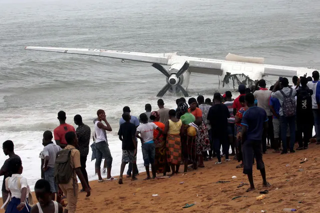 People gather to look at the remains of a cargo plane that crashed in the sea near the international airport in Ivory Coast's main city, Abidjan on October 14, 2017. (Photo by Luc Gnago/Reuters)