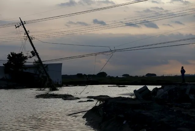 A man looks at the site where a street, houses and electric power poles were destroyed at a residential area flooded by the Kinugawa river, caused by typhoon Etau, in Joso, Ibaraki prefecture, Japan, September 11, 2015 in the dusk. (Photo by Issei Kato/Reuters)