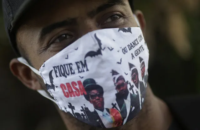 A man wears a protective face mask with a picture of the Ghana's dancing pallbearers, that reads “Stay at home, or dance with us” as he waits outside a public bank, where most of people try to receive emergency aid given by the federal government to the most vulnerable, during the coronavirus disease (COVID-19) outbreak, in Rio de Janeiro, Brazil, May 29, 2020. (Photo by Ricardo Moraes/Reuters)