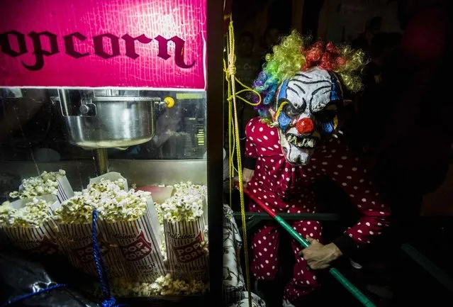A man dressed in a scary clown costume poses for photographs next to a popcorn machine during the celebration of the “Los Agüizotes” in Masaya, Nicaragua, 27 October 2017. (Photo by Jorge Torres/EPA/EFE)