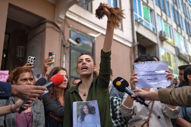 Nasibe Samsaei, an Iranian woman living in Turkey, holds up her ponytail after cutting it off with scissors, during a protest outside the Iranian consulate in Istanbul on September 21, 2022, following the death of an Iranian woman while in custody in Tehran. Mahsa Amini, 22, was on a visit with her family to the Iranian capital Tehran, when she was detained on September 13, 2022, by the police unit responsible for enforcing Iran's strict dress code for women, including the wearing of the headscarf in public. She was declared dead on September 16, 2022 by state television after having spent three days in a coma. (Photo by Yasin Akgul/AFP Photo)