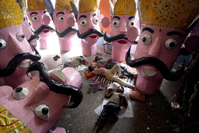 Indian artists rest near the effigies of mythical demon King Ravana as preparations for the Dussehra festival celebrations are ongoing in Jammu, the winter capital of Kashmir, India, 29 September 2014. The effigies are burnt at the Hindu festival Dussehra that commemorates the triumph of Lord Rama over the demon king Ravana, marking the victory of good over evil. (Photo by Jaipal Singh/EPA)