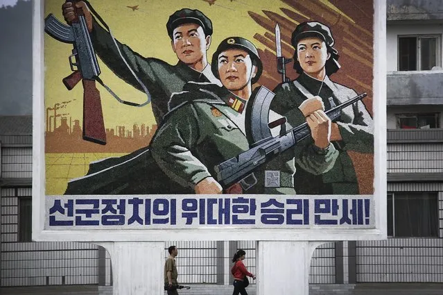 A North Korean man and woman walk under a mural with a message which reads “Long live the great victory of the army-first policy” in the city center of Wonsan on Wednesday, June 22, 2016, in Wonsan, North Korea. (Photo by Wong Maye-E/AP Photo)