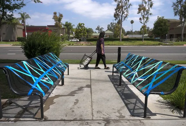 A woman walks past benches taped off for social distancing outside a restaurant, Thursday, July 2, 2020, in La Habra, Calif. California's mood has gone from optimistic to sour as coronavirus cases and hospitalizations are on the rise heading into the July 4th weekend. Gov. Gavin Newsom has ordered bars and indoor restaurant dining closed in most of the state, many beaches are off limits, and he's imploring Californians to avoid holiday gatherings with family and friends. (Photo by Jae C. Hong/AP Photo)
