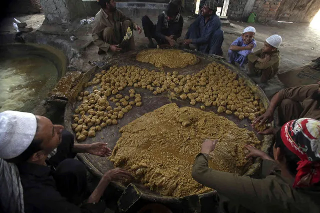 Pakistani farmers boil sugarcane juice and then make balls by hand to make the traditional sweet called “Gurr”, on the outskirts of Peshawar, Pakistan, Sunday, October 30, 2022. (Photo by Mohammad Sajjad/AP Photo)