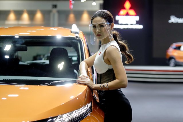 A model wearing a face shield poses with a Mitsubishi vehicle during the media day of the 41st Bangkok International Motor Show after the Thai government eased measures to prevent the spread of the coronavirus disease (COVID-19) in Bangkok, Thailand on July 14, 2020. (Photo by Jorge Silva/Reuters)