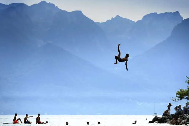 A man jumps into the Geneva Lake after having slipped on a water slide in front of the Swiss and French Alps mountains as they enjoy the sunny and warm weather during the Summerslide Festival in Clarens near Montreux, Switzerland, 03 September 2016. (Photo by Laurent Gillieron/EPA)