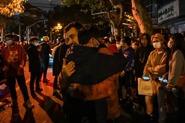 A man hugs another to show support during a manifestation in Shanghai on November 27, 2022, where protests against China's zero-Covid policy took place the night before following a deadly fire in Urumqi, the capital of the Xinjiang region. (Photo by Hector Retamal/AFP Photo)