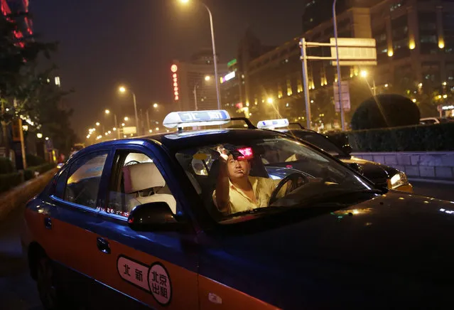 A picture made available on 23 September 2015 shows a Chinese taxi driver putting up the “for hire” sign in his taxi outside a train station in Beijing, China, 17 September 2015. With almost 20 million cars sold last year, China is the largest passenger cars market in the world and chronic traffic congestions in many of its cities like Beijing is one of the reasons why taxi and car hailing smartphone apps offered by Didi Kuaidi and Uber Technologies Inc. are widely popular with commuters. (Photo by How Hwee Young/EPA)