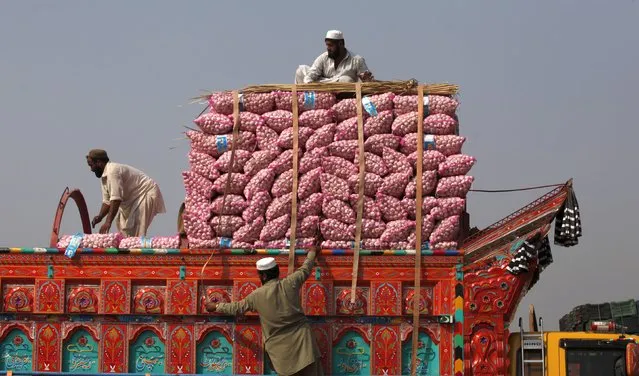 Laborers load sacks of garlic on to a truck at a transport hub on outskirts of Peshawar, Pakistan October 6, 2015. (Photo by Fayaz Aziz/Reuters)
