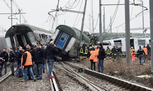Rescue workers and police officers stand near derailed trains in Pioltello, on the outskirts of Milan, Italy, January 25, 2018. (Photo by Reuters/Stringer)
