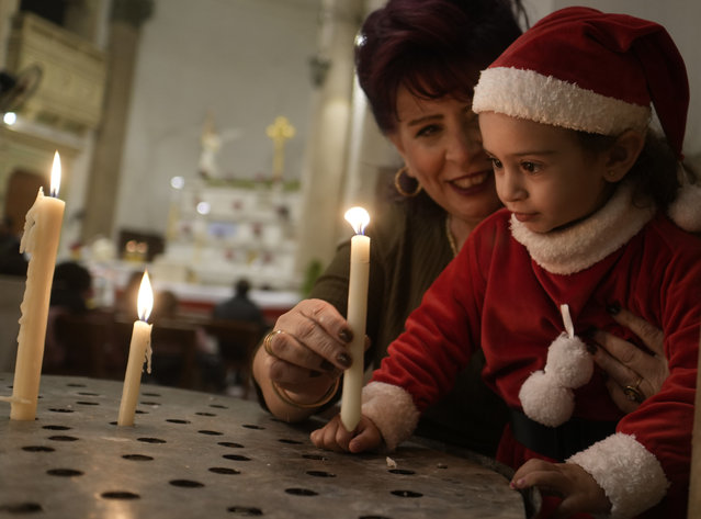 Egyptian Donciel Maykel Nasr, 5, dressed in a Santa Claus costume lights candles during a Christmas Eve Mass at Saint Joseph's Catholic Church in Cairo, Egypt, late Saturday, December 24, 2022. (Photo by Amr Nabil/AP Photo)