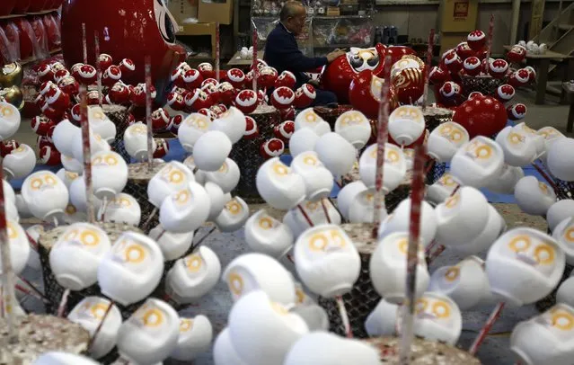 Japanese craftsman Sumikazu Nakata adds the final touches on a Daruma doll, which is believed to bring good luck, at his studio  “Daimonya” in Takasaki, northwest of Tokyo November 23, 2014. (Photo by Yuya Shino/Reuters)