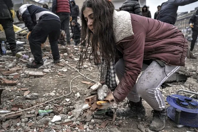 A young women removes debris from a destroyed building as she searches for people with emergency teams in Gaziantep, Turkey, Monday, February 6, 2023. A powerful quake has knocked down multiple buildings in southeast Turkey and Syria and many casualties are feared. (Photo by Mustafa Karali/AP Photo)