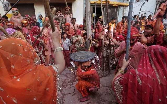 Indian women from Nandgaon hit villagers from Barsana. During Lathmar Holi the women of Nandgaon, the hometown of Krishna, beat the men from Barsana, the legendary hometown of Radha, consort of the Hindu God Krishna, with wooden sticks in response to their teasing as they depart the town. (Photo by Manish Swarup/Associated Press)