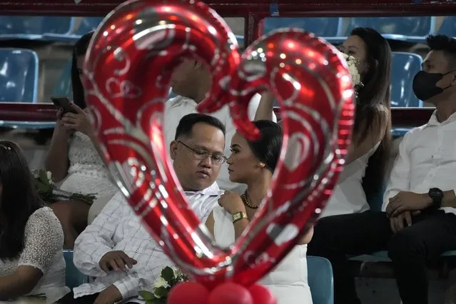 A groom checks his bride's dress as they wait for ceremonies to begin at a mass wedding in San Juan city, Manila, Philippines to celebrate Valentines day Tuesday, February 14, 2023. Aside from the cash gift and free wedding reception for their guests, the city mayor also promised the 63 couples free hospital services upon giving birth in San Juan. (Photo by Aaron Favila/AP Photo)