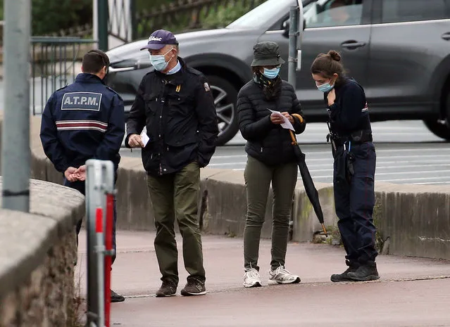 Police officers check documents to ensure that confinement measures due to the coronavirus are upheld in Saint Jean de Luz, southwestern France, Tuesday, November 3, 2020. French supermarkets are banned from selling flowers and books but they can still sell baby care products, according to a decree published Tuesday laying out new rules for what are considered “essential” items during a monthlong lockdown effort to slow virus infections and save lives. (Photo by Bob Edme/AP Photo)