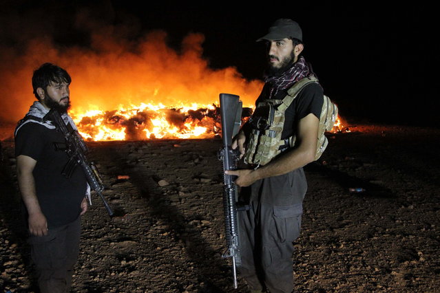 Afghan security officials keep watch as seized drugs are burned in the Spin Boldak district of Kandahar, Afghanistan, 20 August 2025 (issued 21 August 2025). Afghan officials set fire to over 13,000 kilograms of drugs that had been confiscated over the past year in Kandahar city and the Spin Boldak district, with most reportedly smuggled from neighboring Pakistan, according to Mullah Asadullah Jamshid, spokesperson for the Kandahar police headquarters. (Photo by Qudratullah Razwan/EPA)