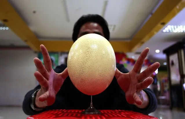 Cui Juguo, 50-year-old security guard, balances an ostrich egg on a needle in Changsha, Hunan province December 10, 2014. Cui has practiced balancing eggs on needle for over 6 years and he once succeeded balancing three eggs within a minute on a local television program, local media reported. (Photo by Darwin Zhou/Reuters)