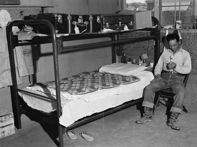 A man sits in a barrack in the Twin Falls, Idaho, between 1942 and 1944. Each was divided into six apartments, each measuring 14ft by 16ft. A typical one-room apartment, which could house four individuals, contained two pairs of bunk beds and a table with chairs. (Photo by Russell Lee/Japanese American National Museum)