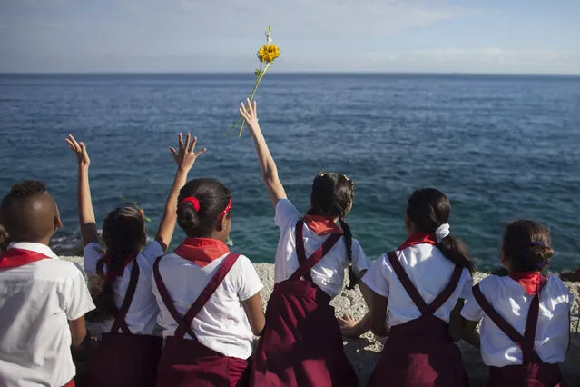 Schoolchildren throw a flower into the sea in honor of rebel revolutionary commander Camilo Cienfuegos from Havana's seafront boulevard “Malecon” October 28, 2014. Cienfuegos was a commander of Fidel Castro's rebel army but died less than a year after their victory when his plane disappeared over the ocean on October 28, 1959 en route from Havana to Camaguey. The plane and his body were never found. (Photo by Alexandre Meneghini/Reuters)